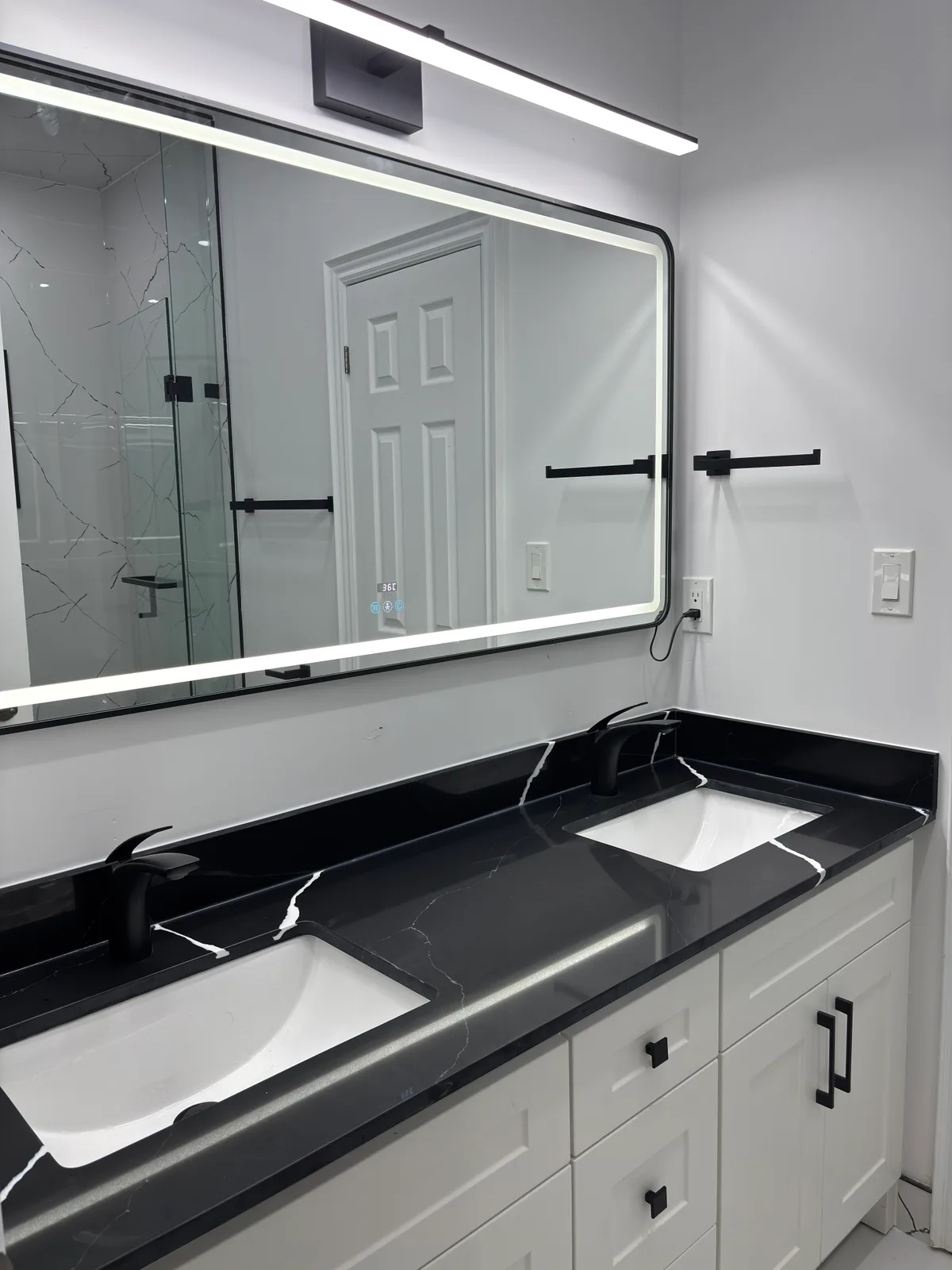 A double vanity and glass shower anchor this black-and-white bathroom