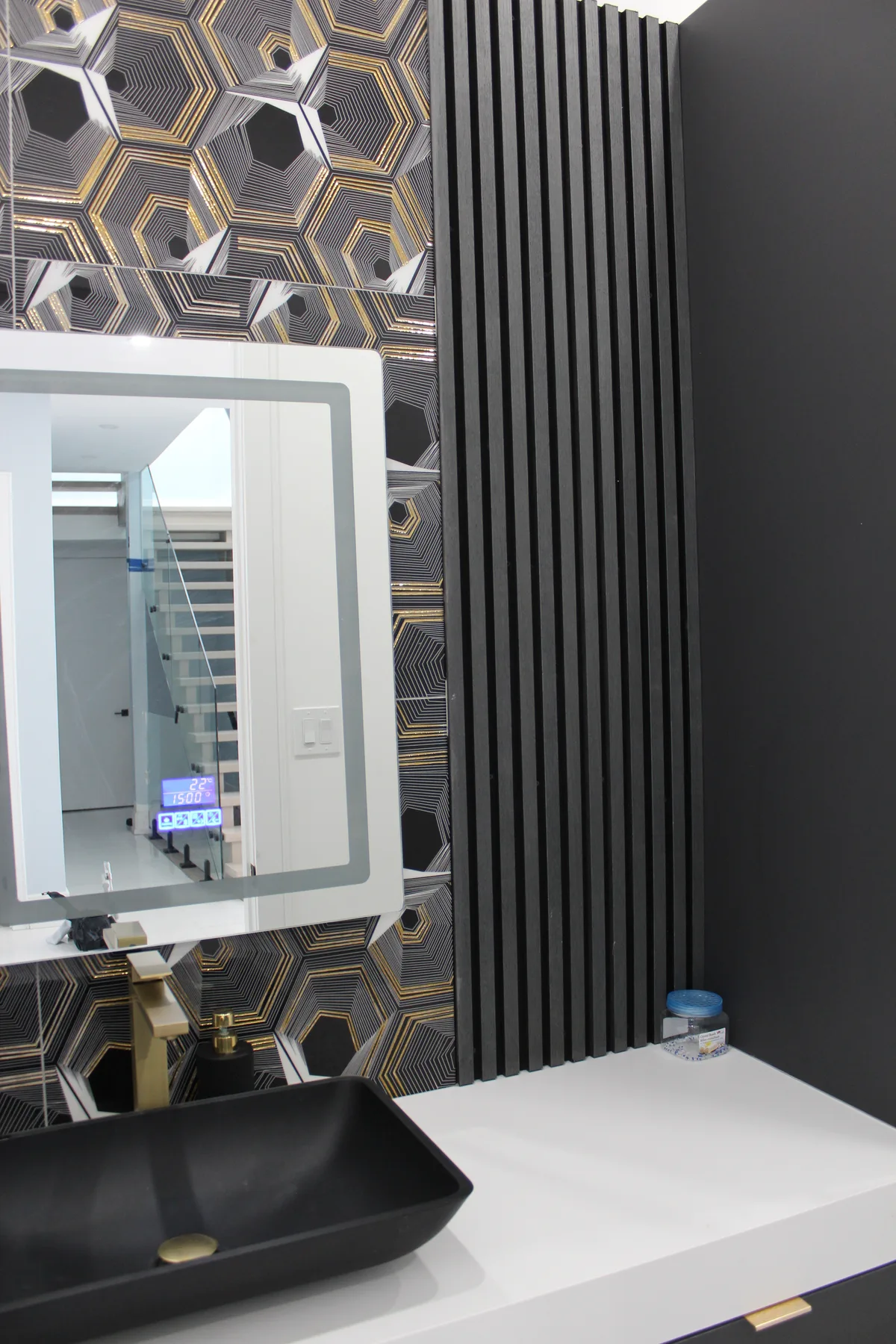 A geometric feature wall and black basin give this powder room a bold identity